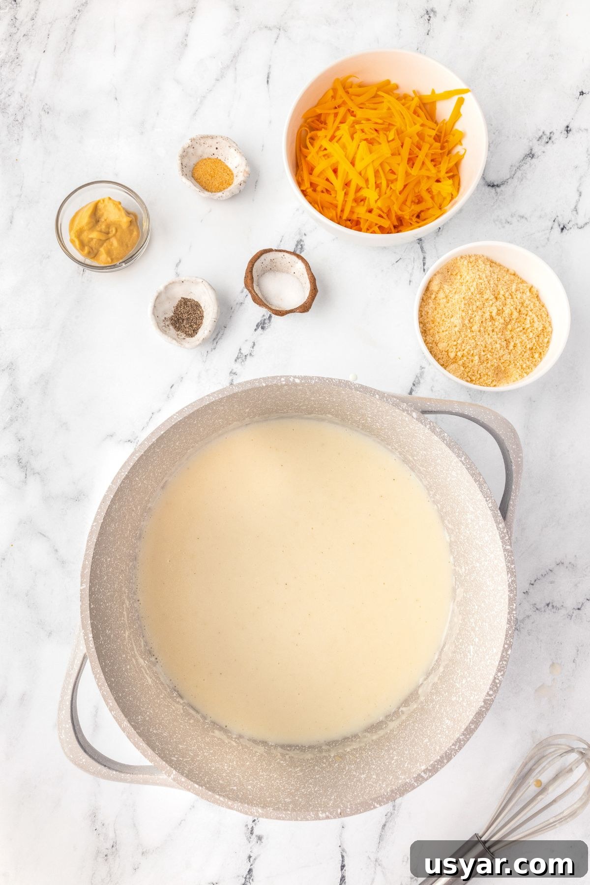 Creamy Stovetop Macaroni and Cheese 7 Creamy cheese sauce with shredded cheddar, spices, and ingredients ready for cooking.
